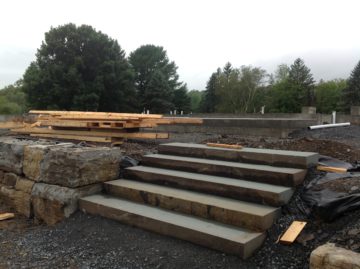 Stone steps integrated with natural stone retaining wall